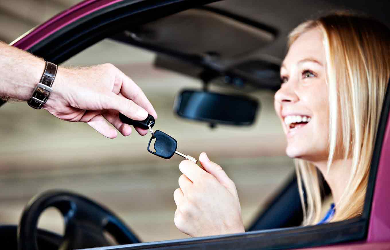 smiling girl receiving car keys from a man